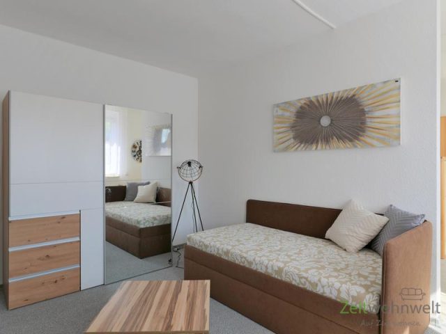 Schlafcouch und verspiegelter Kleiderschrank
