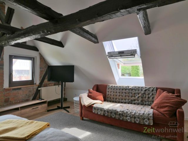 TV und Couch im großen Schlafzimmer